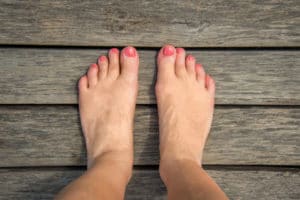 Woman's bare feet with painted nails on a wooden floor